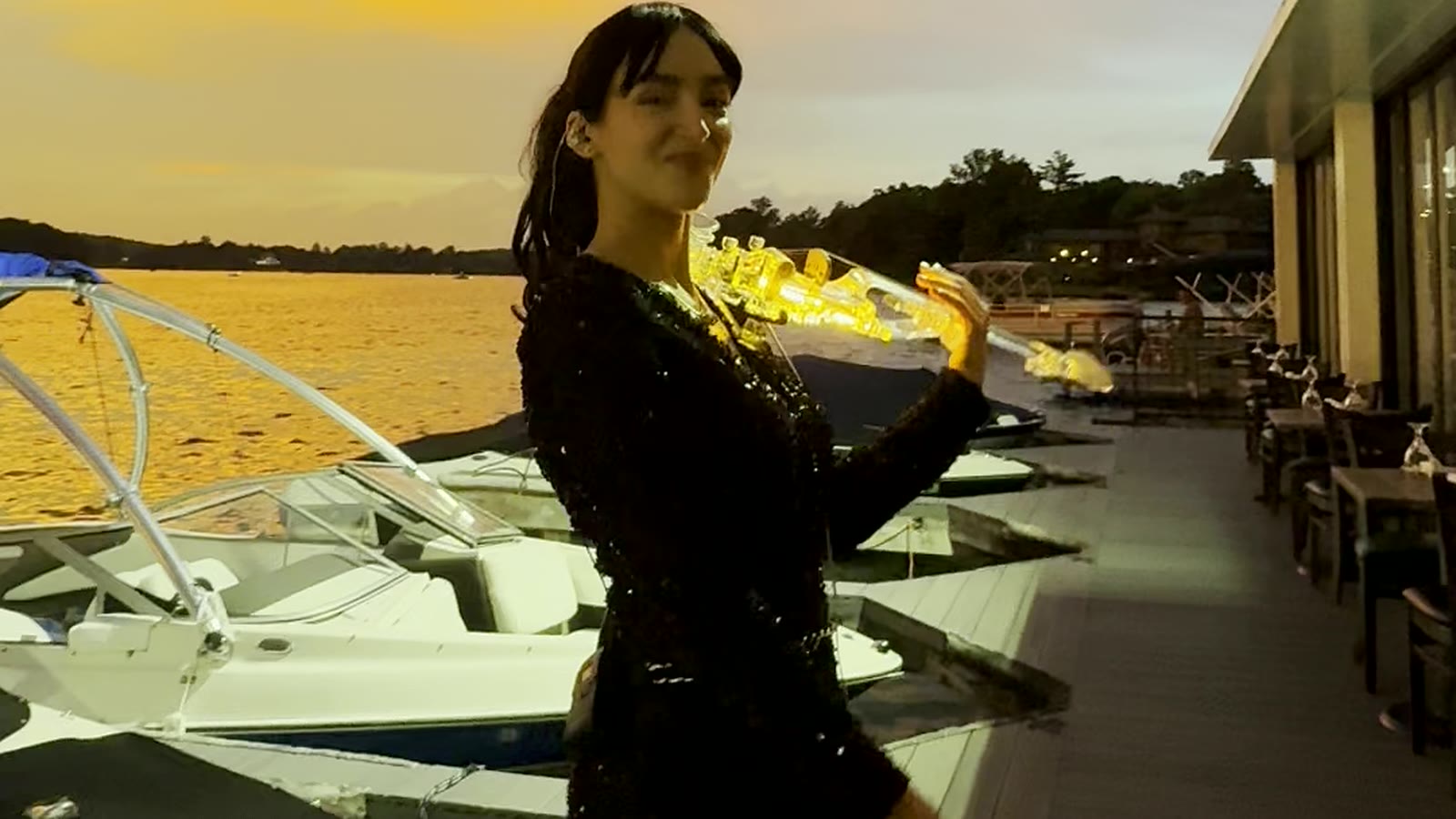 Sadie Varius playing her glowing transparent violin on a dock at dusk