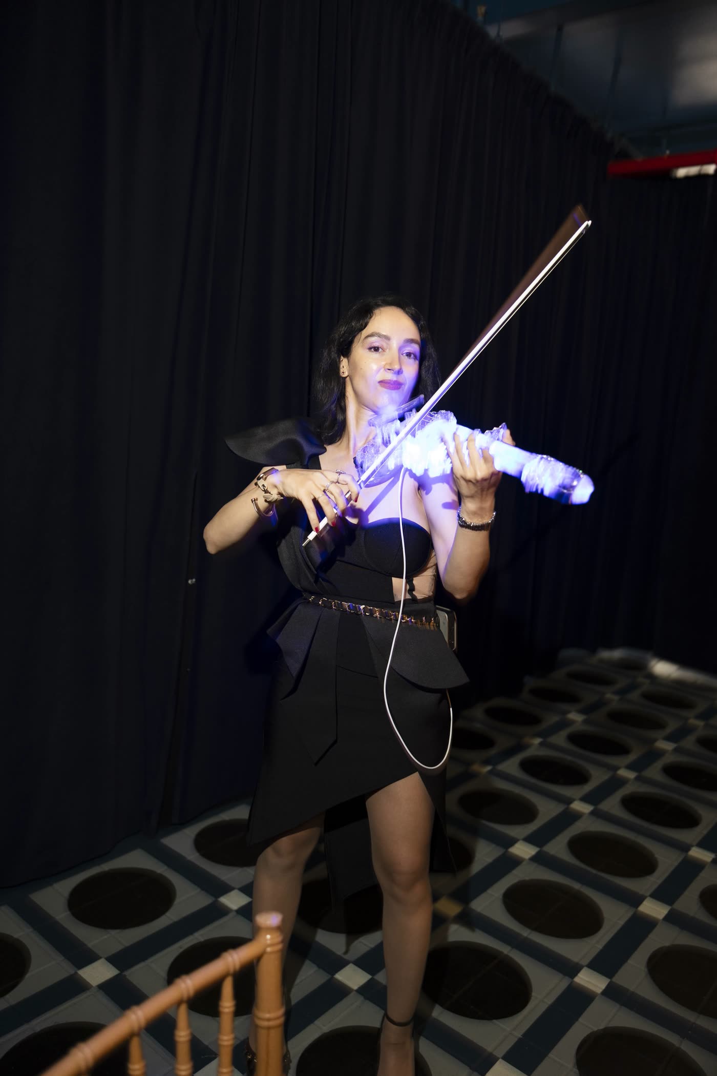 Sadie playing the lit violin in a dark room